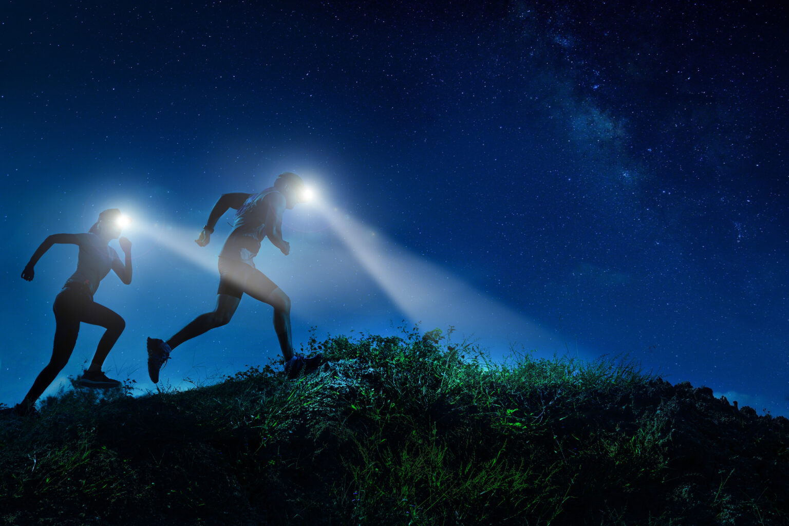 Night trail runner of men and women running on the mountain.at night milky way